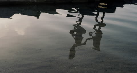 Couple's Reflection on Rippling Waters of Serene Beach