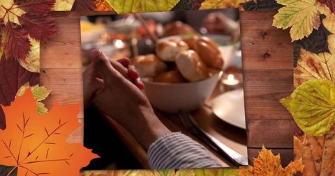 Clasping hands at rustic autumn dinner table, sharing warmth, bread rolls and candlelight