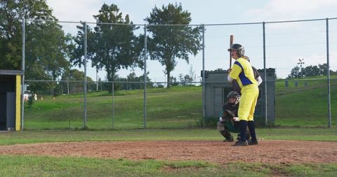 Female softball players battling at home plate on dirt infield