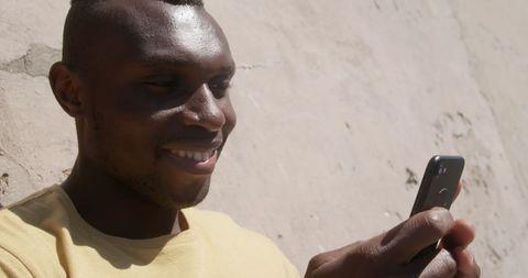 Smiling man texting at beach with smartphone
