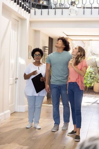 Couple touring modern foyer with african american agent pointing to pendant light