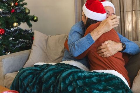Father and daughter embracing on holiday couch by christmas tree