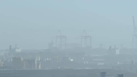 Misty Urban Cityscape with Crane Structures and Shipping Docks