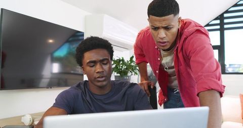 Diverse Male Team Collaborating on Laptop in Modern Workspace