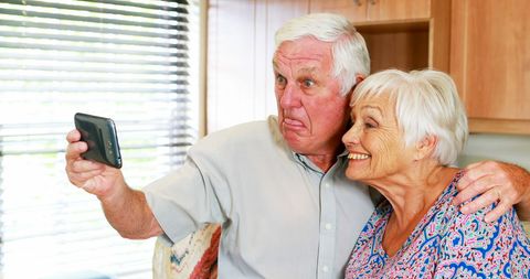 Joyful Senior Couple Taking Fun Selfie in Modern Kitchen
