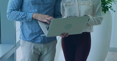 Close collaboration with laptop in contemporary office hallway