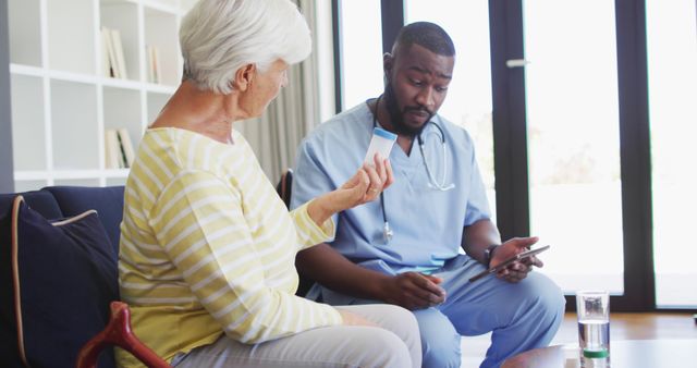 Image of african american male doctor giving medicines to caucasian senior woman. seniors health and nursing home lifestyle concept.