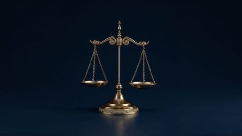 Golden balance scale on dark background reflecting justice theme