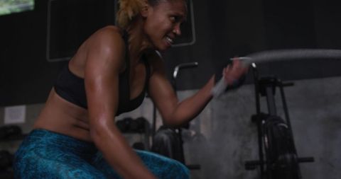 Determined woman exercising vigorously with rope at gym