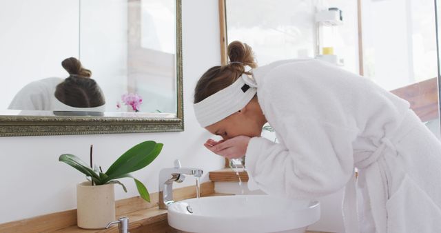 Woman washing face in bathroom in morning routine - Download Free Stock Images Pikwizard.com