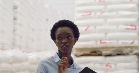 Thoughtful Woman Analyzing Logistics in a Warehouse