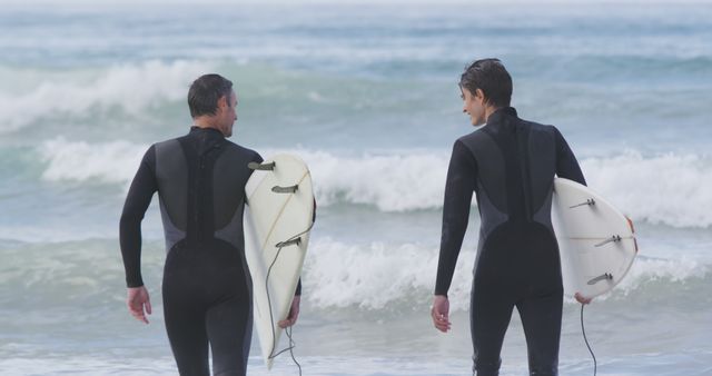 Two Surfers Holding Their Boards Walking Along Beach Towards Ocean Waves - Download Free Stock Images Pikwizard.com
