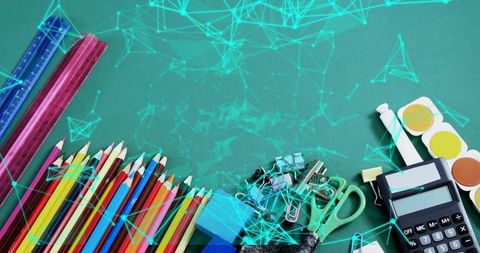 Colorful school supplies arranged on green chalkboard with calculator and paints