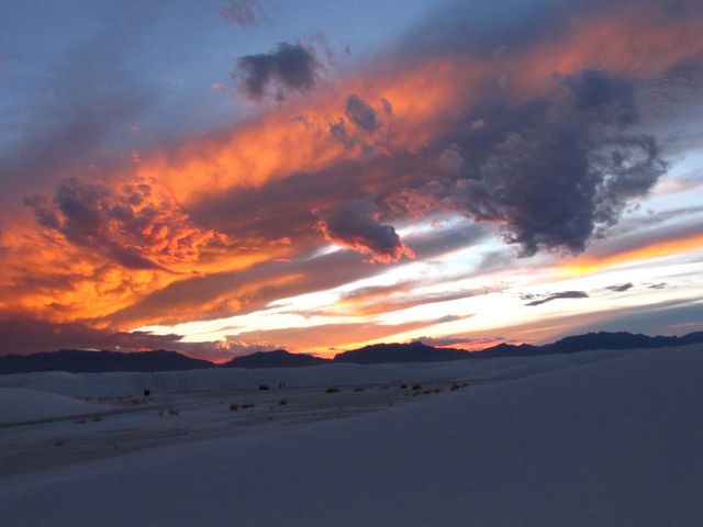 Vibrant sky during sunset over expansive white sand dunes with dramatic clouds. Perfect for use in travel magazines, brochures highlighting natural landmarks, websites focusing on natural beauty and landscape photography, and for inspiring social media posts about exploring nature.