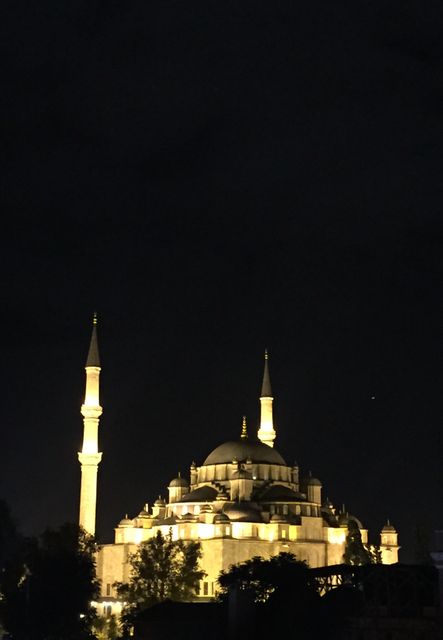 Illuminated mosque with visible minarets against night sky. Useful for articles, travel blogs, religious content, website backgrounds, or educational materials about Islamic architecture.