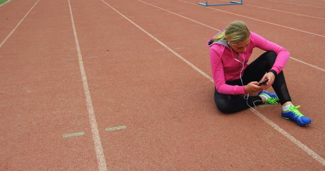 Woman Sitting on Running Track Tuning Media Player and Wearing Sportswear - Download Free Stock Images Pikwizard.com