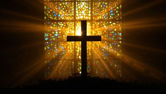 Sunlit cross silhouette with radiant stained glass halo and golden rays