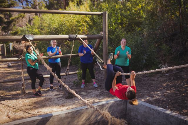 Fit woman climbing a rope during obstacle course training in the boot camp