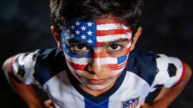 Close-up portrait young soccer fan with american flag face paint and intense gaze