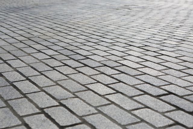 Cobblestone road surface with regular stone pattern. Suitable for backgrounds, architectural concepts, urban designs, and historical themes.