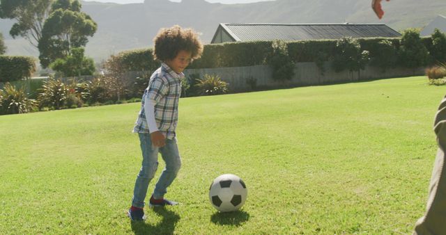 Young child enjoying a soccer game on a well-maintained green lawn in a backyard. This scene captures a casual outdoor activity perfect for family moments, sports promotion, children's sports programs, or outdoor playtime advertisements.