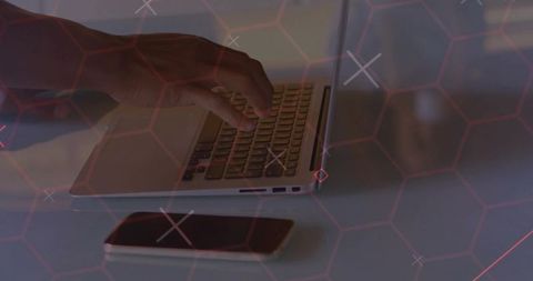 Close-up of Hand Typing on Laptop with Red Hexagonal Grid Overlay