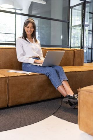 Professional Young Woman on Laptop in Modern Office Lounge