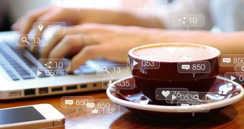 Coffee cup beside laptop typing with social media notifications overlay for remote work