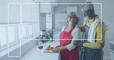 Senior couple cooking together in sunlit kitchen smiling while chopping fresh vegetables