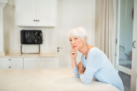 Senior woman in modern kitchen exuding calm and contemplation