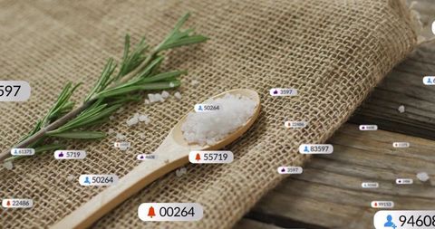 Resting wooden spoon with coarse sea salt and rosemary on burlap rustic tabletop
