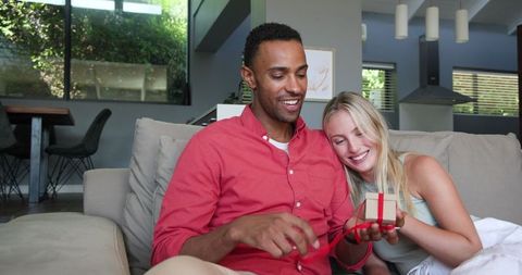 Happy Couple Sharing Gift Moment In Modern Living Room