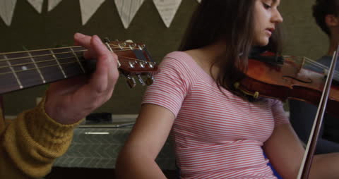 Teenagers Rehearsing with Guitar, Violin, and Saxophone in Music Class