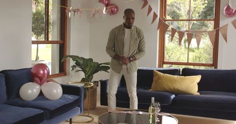 Man arranging festive balloons in cozy living room