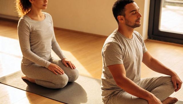 Couple practicing mindfulness meditation and gentle yoga in sunlit home studio