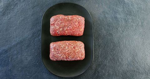 Raw beef patties on black plate