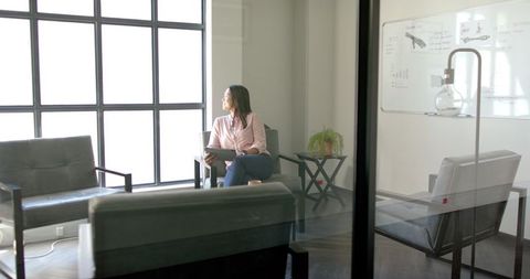 Businesswoman Thinking While Sitting in Modern Office with Tablet