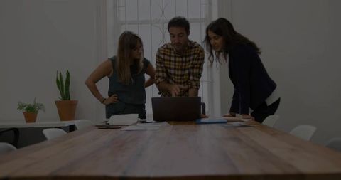 Team Discussion Over Laptop in Modern Office Setting