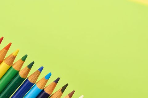 Bright sharpened colored pencils lined diagonally on lime green background with copy space