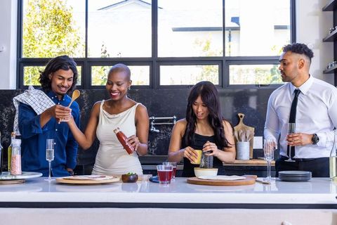 Multicultural friends preparing appetizers at modern kitchen island during party