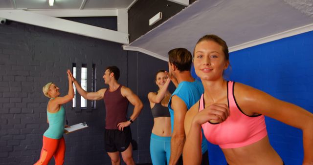 Group of individuals engaging in a fitness training session, sharing high fives as a sign of motivation and teamwork. Ideal for illustrating concepts of wellness, group exercise, active lifestyle, teamwork in fitness, and community exercise sessions.