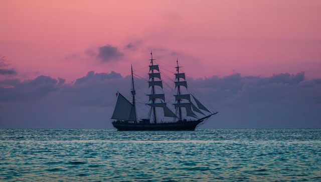 Three-masted ship at sea during tranquil lavender dusk