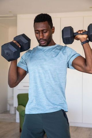 Man Lifting Dumbbells in Home Gym for Strength and Wellness