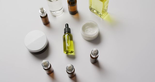 Various skincare and cosmetic bottles scattered on white background. Items include dropper bottles, jars with cream, and clear liquid containers. Useful for beauty, skincare, and wellness blogs, advertisements, product presentations, and e-commerce websites showcasing beauty products.