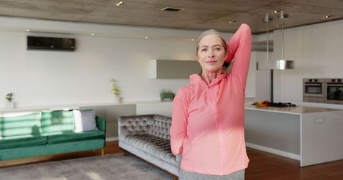 Senior Woman Standing and Stretching in Modern Home Environment