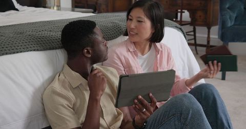Diverse Couple Engaged in Leisure at Home with Tablet and Knitting