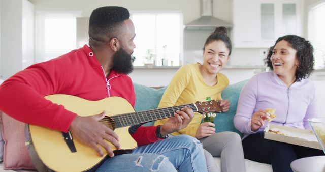 Happy, diverse female and male friends playing guitar and listening at home in slow motion - Download Free Stock Photos Pikwizard.com