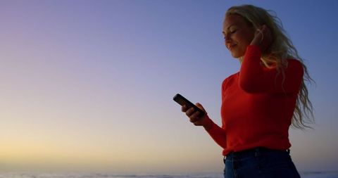 Young Woman Texting on Beach During Sunset