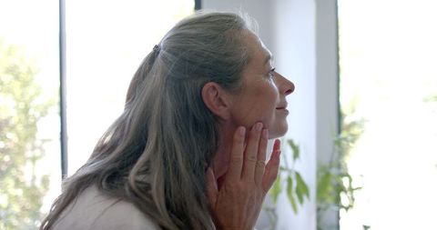 Mature woman touching face in thoughtful quiet reflection