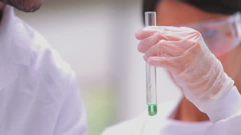 Lab Scientists Collaborating on Experiment with Green Chemical Solution